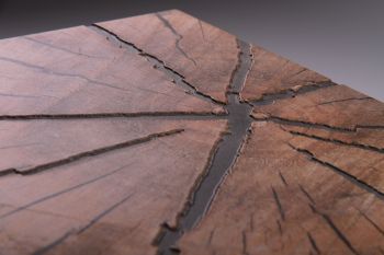 Detalle en ángulo de un azulejo impreso con relieve, donde las grietas de la madera quedan hundidas y la veta sobresale